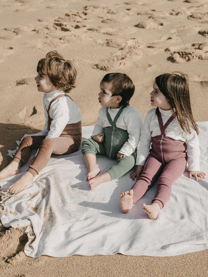 Tre spedbarn i myke barneklær og ullbukser på stranden, perfekt for babyutstyr 0-8 år