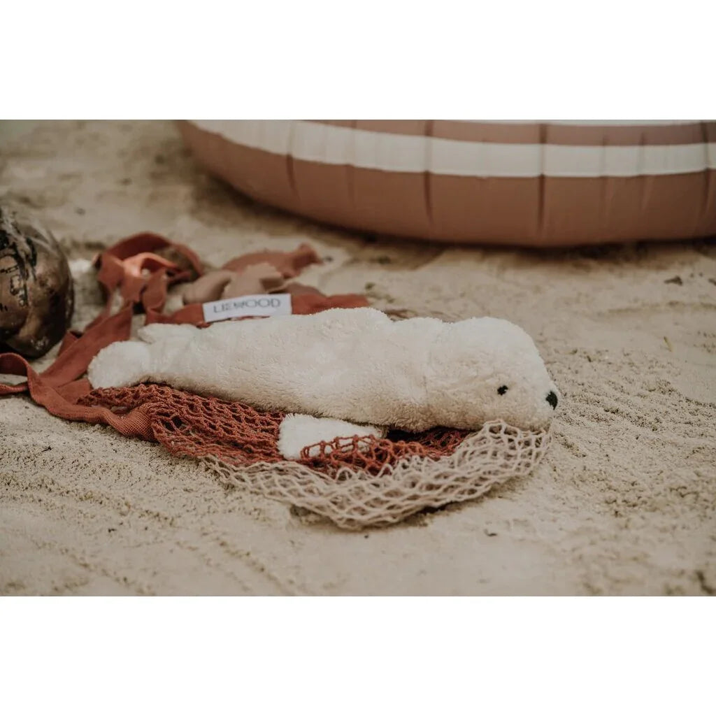 Myk hvit sel plys i nett på sand, perfekt babyutstyr for 0-8 år