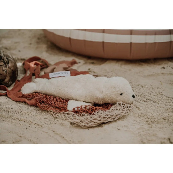 Myk hvit sel plys i nett på sand, perfekt babyutstyr for 0-8 år