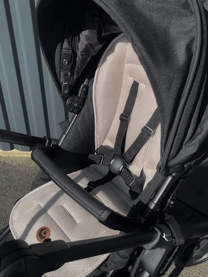 Svart barnevogn med beige mesh-sete og sikkerhetsbelter, perfekt for babyutstyr 0-8 år