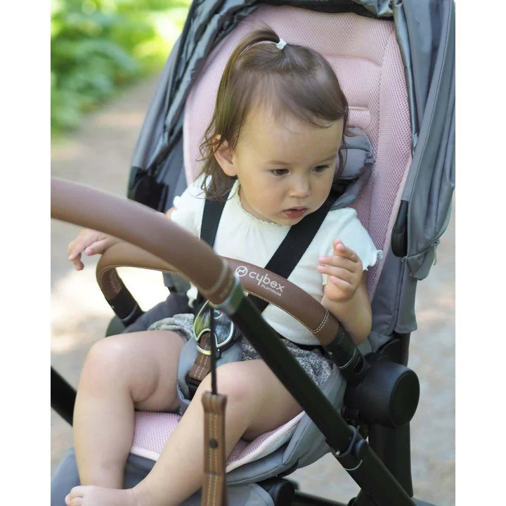 Liten baby i Cybex barnevogn med rosa sete, ute i naturen