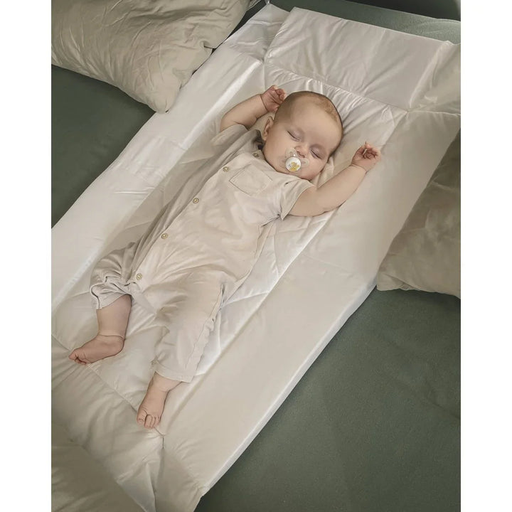 Søvende baby i myk, lys barneklær på seng med sengetøy, perfekt for bebis 0-8 år