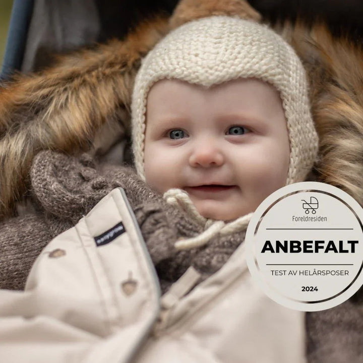 Liten baby i varm ullhette og vinterjakke, anbefalt av foreldresiden 2024