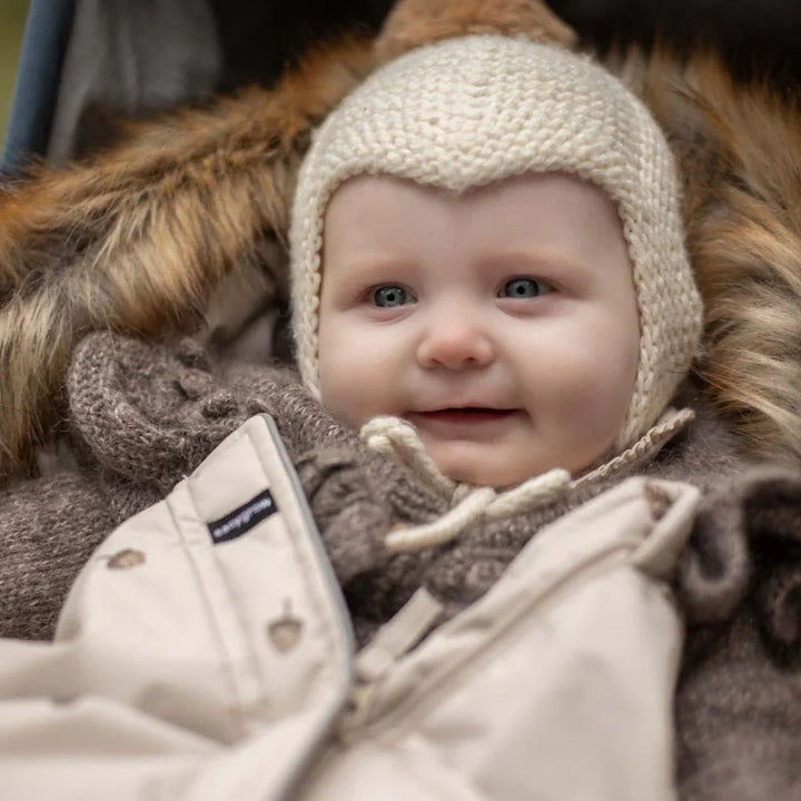 Smilende baby i varm ullhette og vinterjakke, perfekt barneklær for kaldt vær