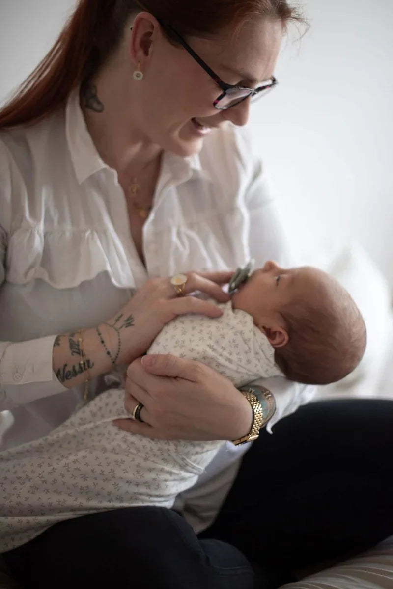 Mor holder nyfødt baby i myk, mønstret barneklær – perfekt for 0-8 år