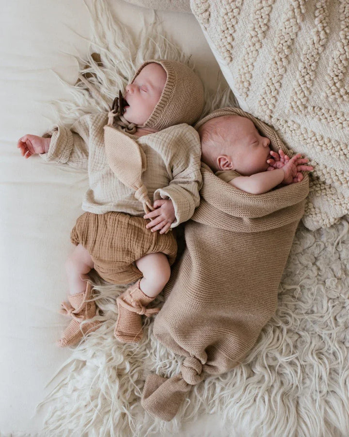 To nyfødte i myke ullklær og strikkede hette, hviler på flausk teppe – perfekt babyutstyr for 0-8 år.