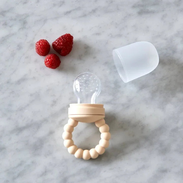 Beige babyfôringspåse med perlegrisp, røde hallon og silikondeksel på marmor