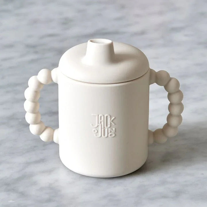 Hvit sippy cup med perlehåndtak og Jack &amp; Jugs logo, perfekt for spedbarn og småbarn.