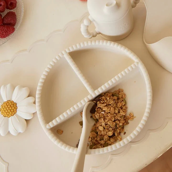 Hvit delte tallerken med granola og skje, perfekt for baby og småbarns måltider