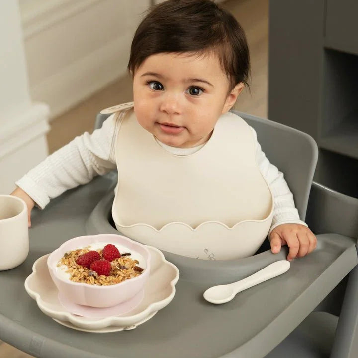 Baby i høysete med mat, myk babyskjorte og skål med jordbær og müsli