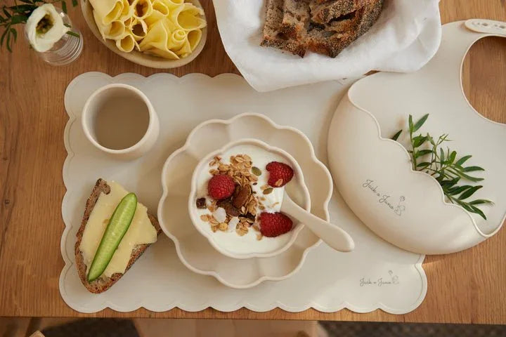 Barnemat med yoghurt, bær og korn, servert på blomsterformet tallerken og matlue for spedbarn