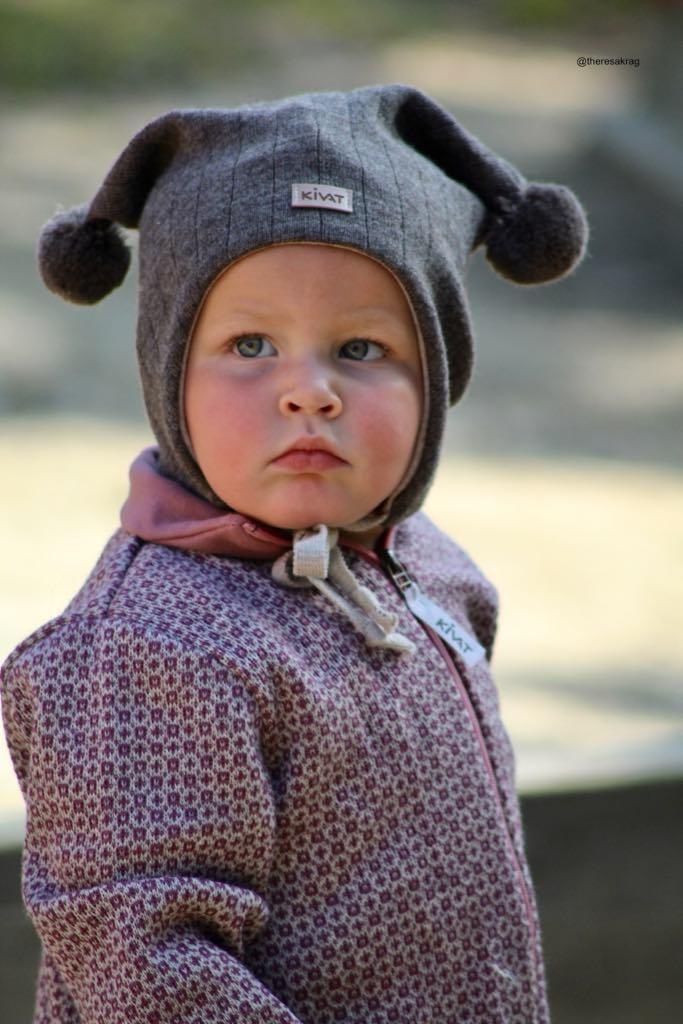 Liten baby i myk ullhette og mønstret barneklær, perfekt for vinter og daglig bruk.