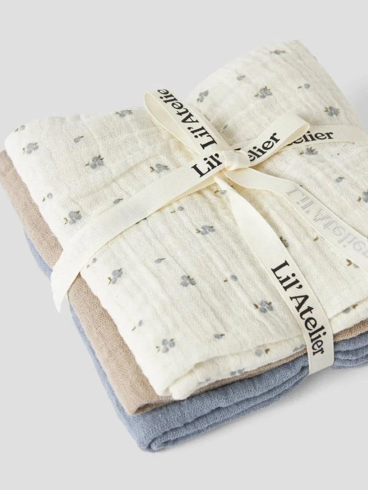 Myke muslin babykluter i blå, beige og hvit med blomstermønster, bundet med Lil’Atelier-ribe