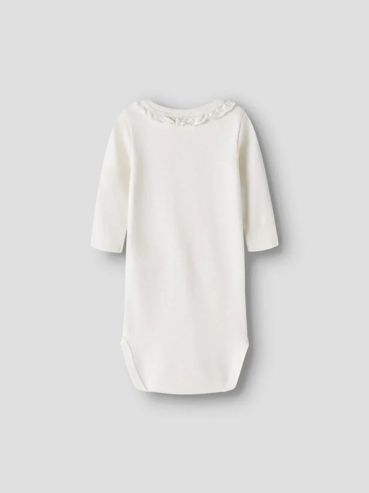 Hvit babybody med lange ermer og blomsterdetalj rundt halsen, myk og bekvem for spedbarn.