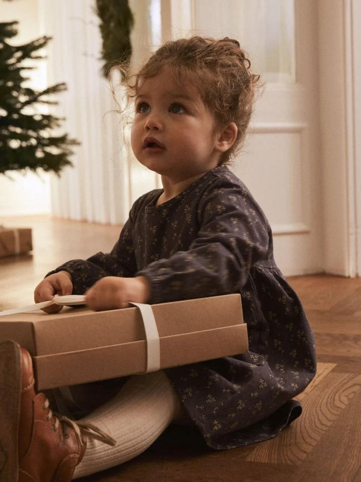 Liten jente i myk barneklær med julegave, perfekt for babyutstyr 0-8 år