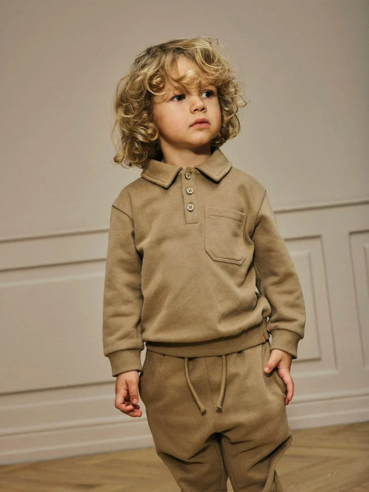 Liten gutt i myk beige barneklær med poloskjorte og bukser, perfekt for 0-8 år