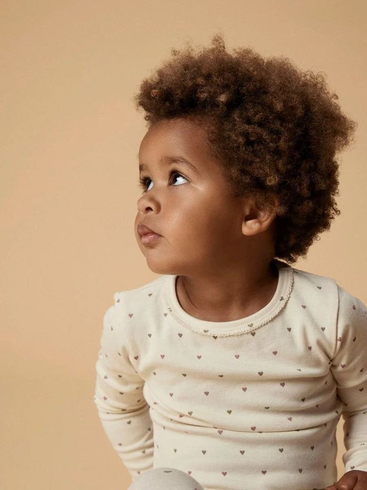 Barn i myk, hvit langærmet body med små hjerteprint, ideell for baby og småbarn 0-8 år