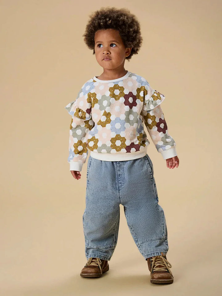 Barn i fargerik blomstertrøye med rynker og blå jeans, myk barneklær for 0-8 år