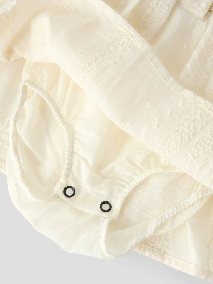Myk babybody i cremefarge med knapper og teksturert stoff, perfekt for spedbarn 0-8 år