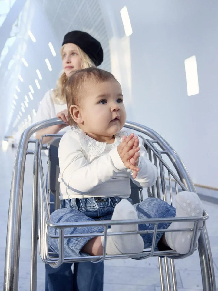 Barn i vogn med hvit genser og jeans, myke babyklær for 0-8 år