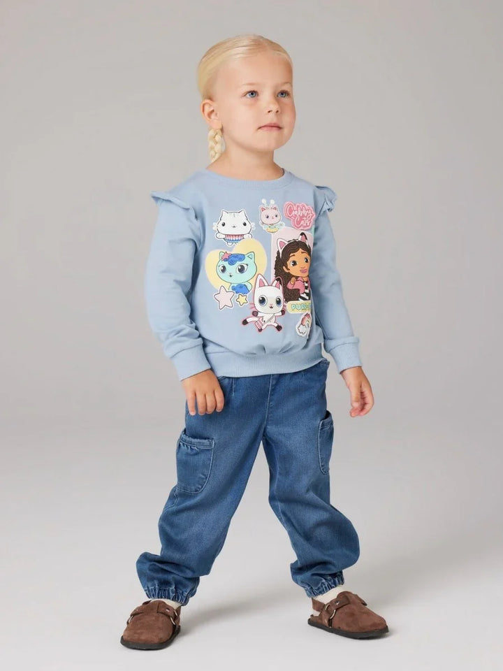 Liten jente i blå genser med katteteikningar og jeansbukser, barneklær 0-8 år