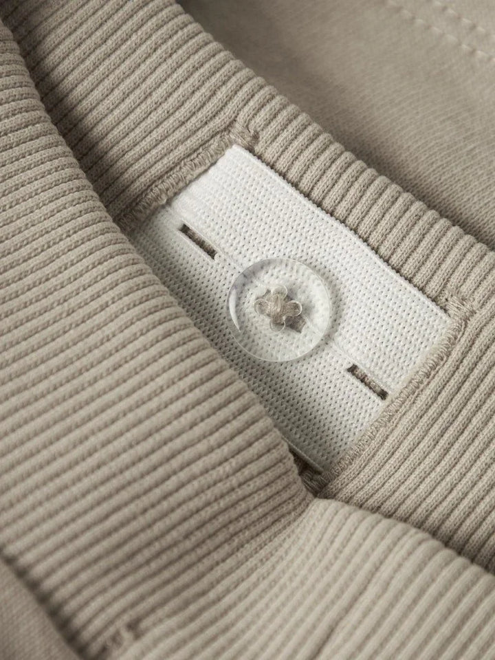 Myk beige barnekjole med ribbet tekstur og gjennomsiktig knapp