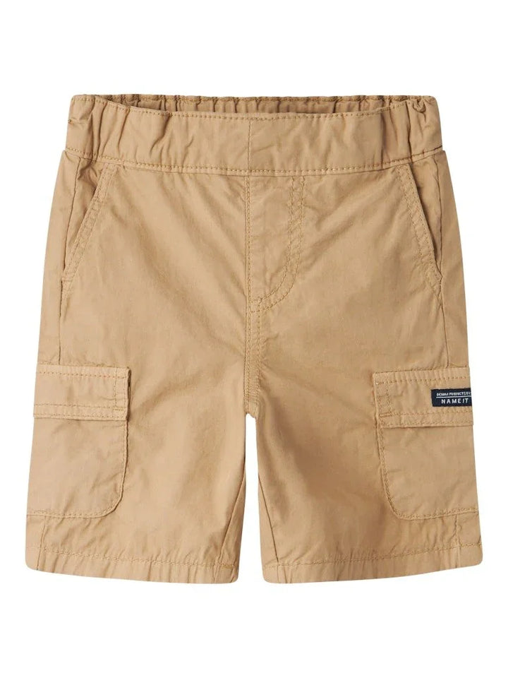 Beige barnebukser med lommer og elastisk liv, perfekt for små barn og sommeraktiviteter.