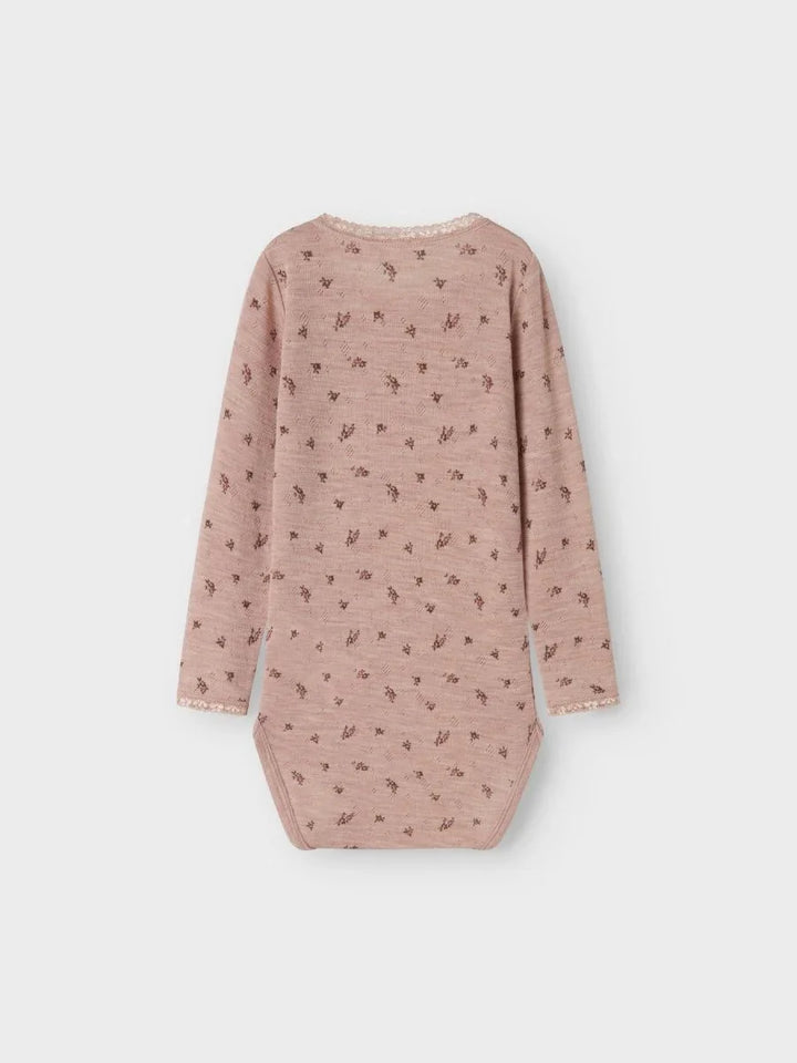 Myk rosa babybody med blomstermønster og kantdetaljer, perfekt for spedbarn og småbarn.