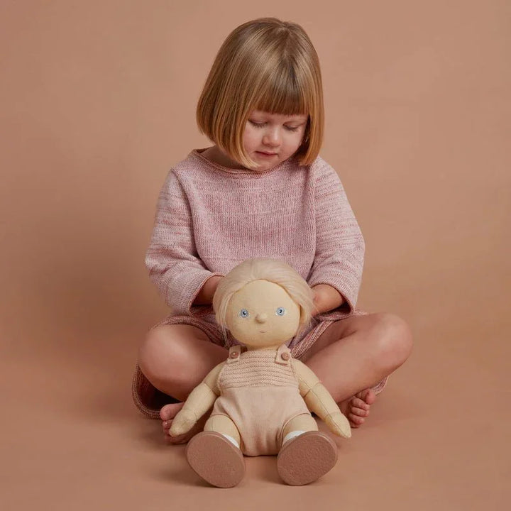 Liten jente i myk rosa genser holder en ulldukke, perfekt barneklær og leketøy for 0-8 år