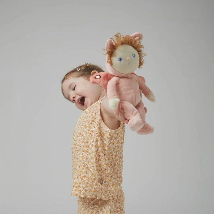 Liten jente i blomsterpyjamas holder en rosa dukke med krøllete hår, myke barneklær for 0-8 år