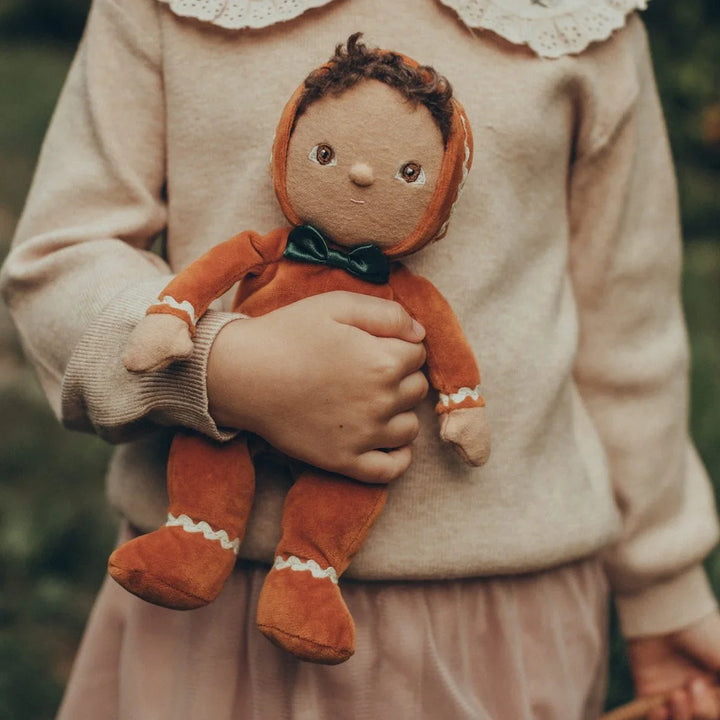 Barn holder myk stoffdukke i orange med grønn slips, perfekt for babyutstyr og barneklær 0-8 år