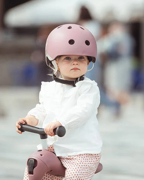 Liten gutt i rosa hjelm på barnebil, myke barneklær og trygg lek for spedbarn 0-8 år