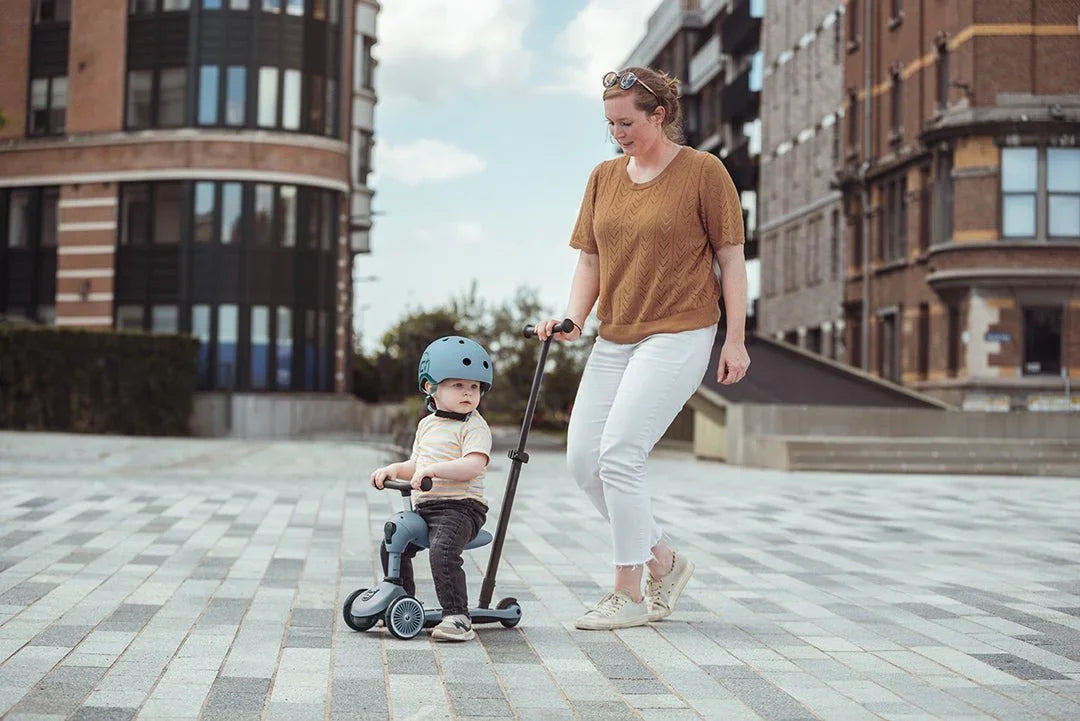 Mor og baby på sparkesykkel i byen, barneklær og sikkerhetshjelm