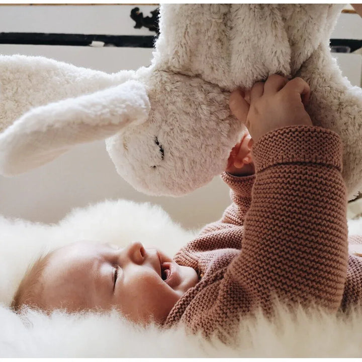 Liten baby i myk strikket genser leker med flausk kanin, perfekt for 0-8 år
