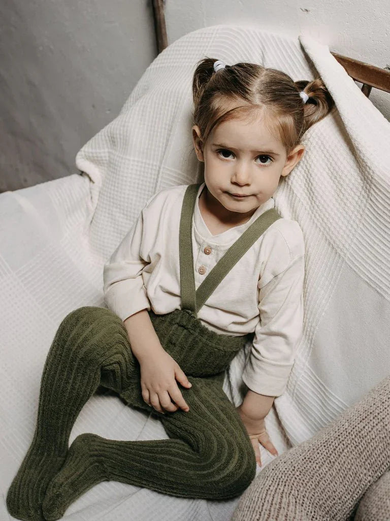 Liten jente i grønne strikkede bukser og hvit skjorte, myke barneklær for 0-8 år