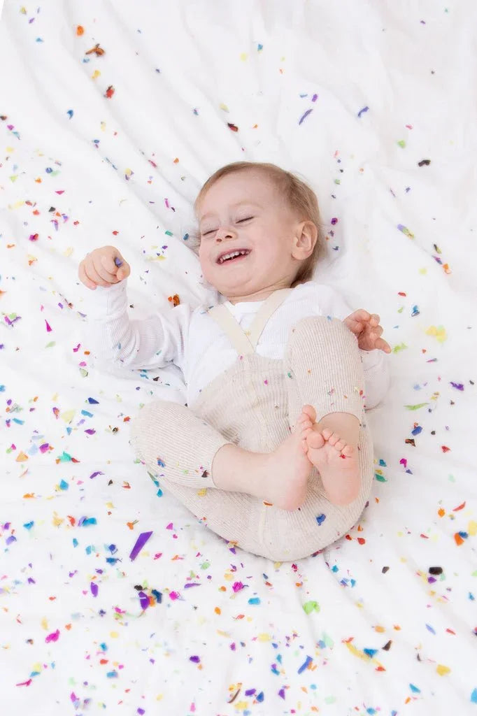 Liten baby i myke barneklær med fargerikt konfetti, perfekt for 0-8 år