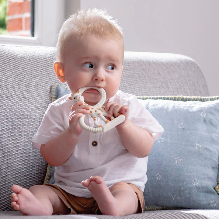 Liten baby med giraffetannring, myke barneklær og stjernepude